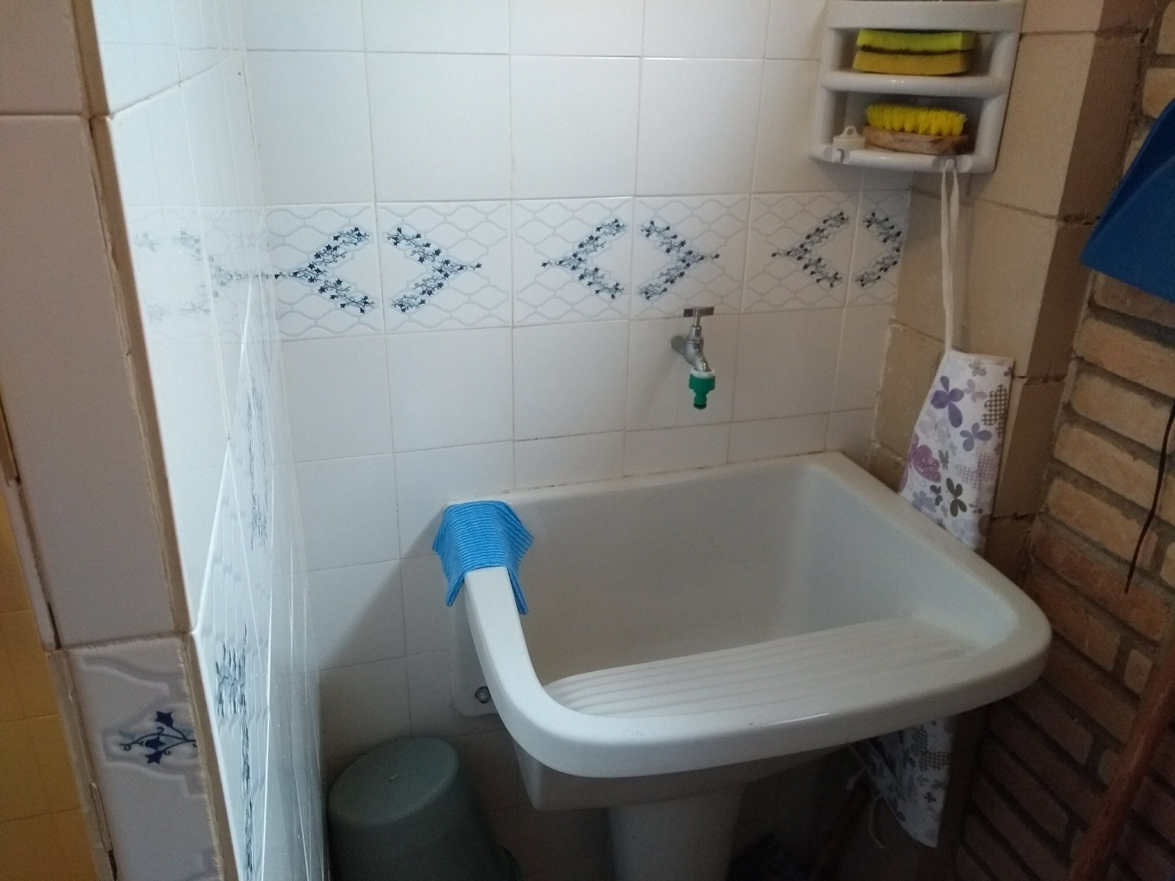 A bathroom with a white sink, a green trash bin, and a blue towel.