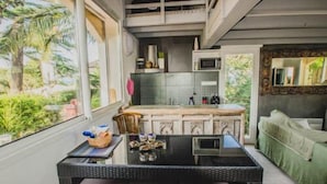 A modern kitchen with a large window, a dining area with a table and chairs, and a green sofa in a living area.