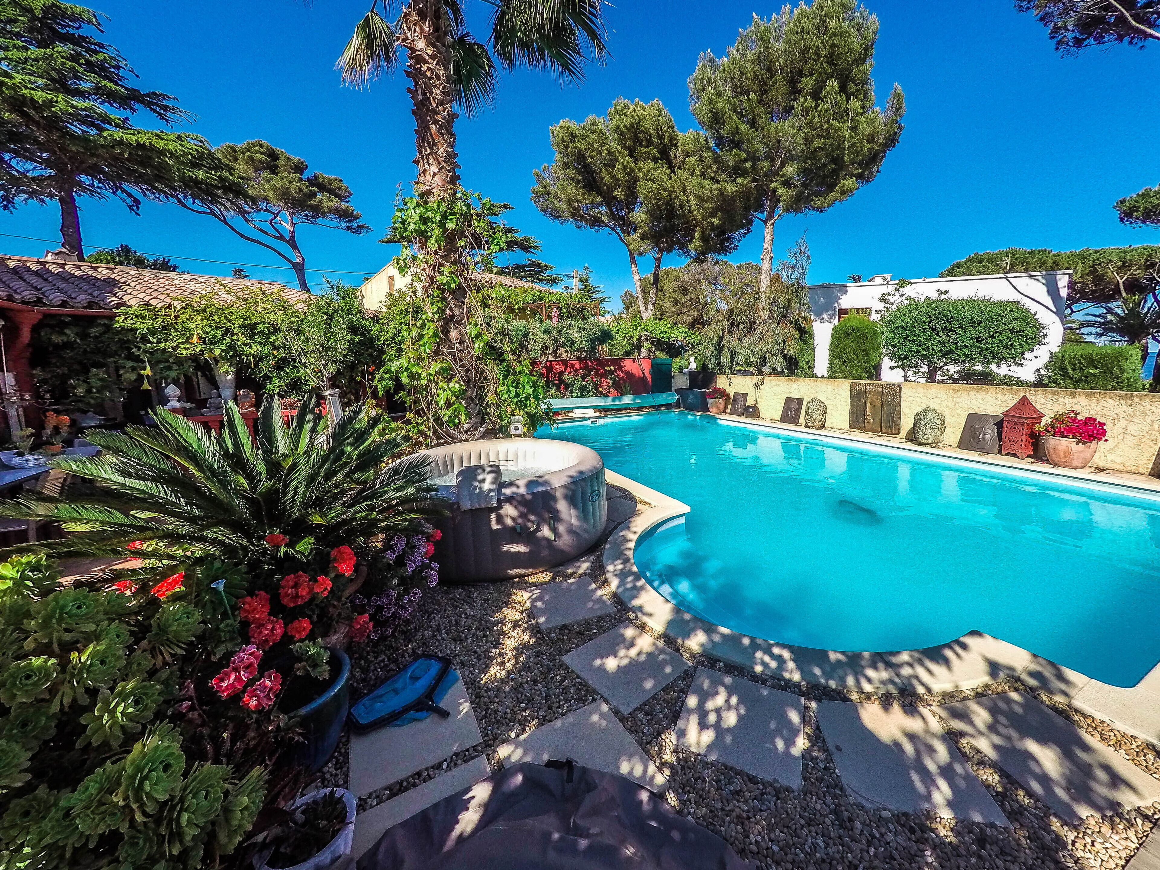 A swimming pool with a stone deck, surrounded by potted plants and trees.