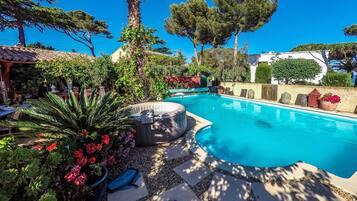 A swimming pool with a stone deck, surrounded by potted plants and trees.