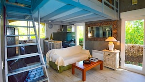 A living room with a sofa, a coffee table, a ladder, and a kitchen area in the background.