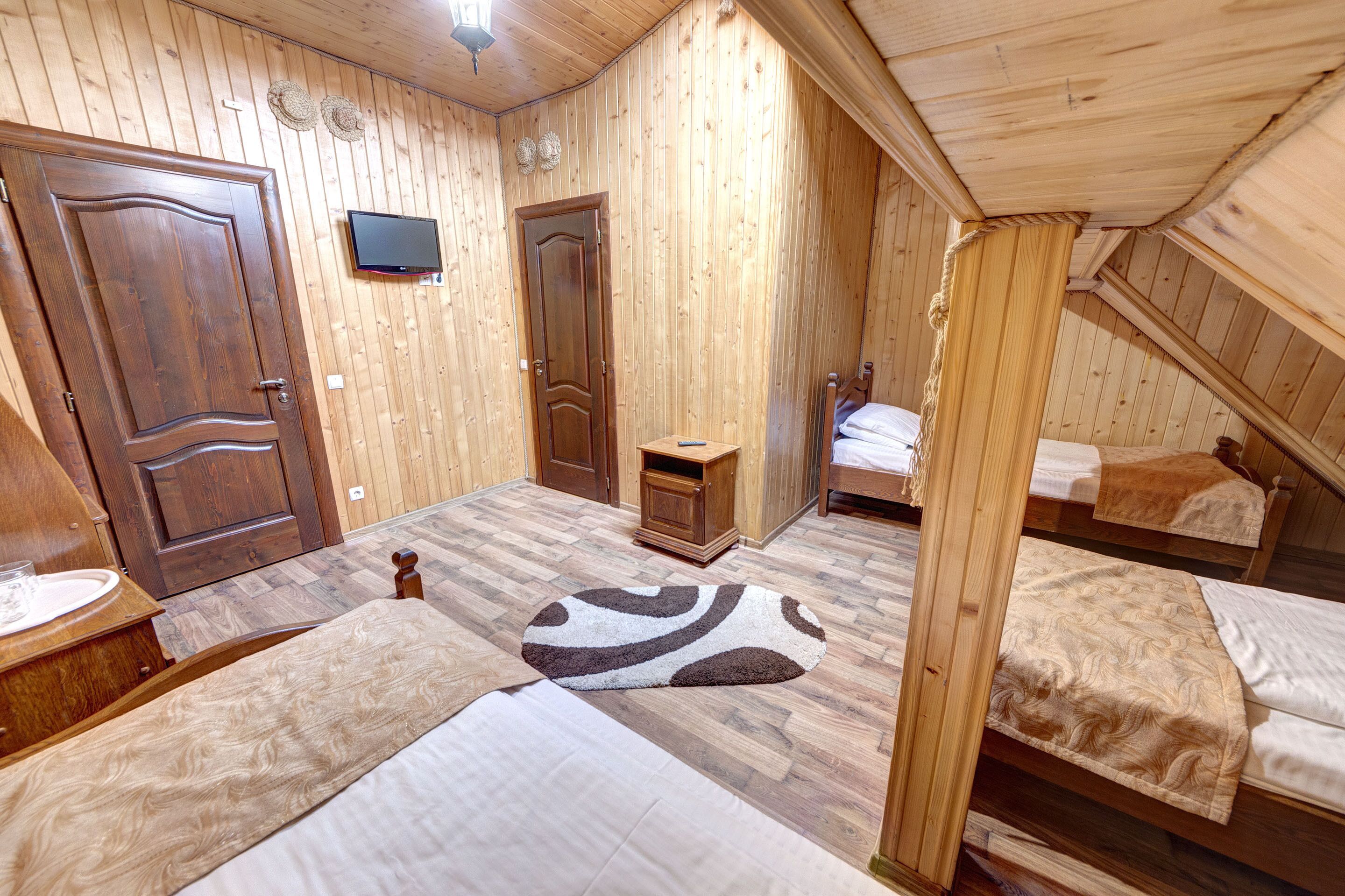 Une pièce en bois avec deux lits, une télévision et une petite armoire en bois.