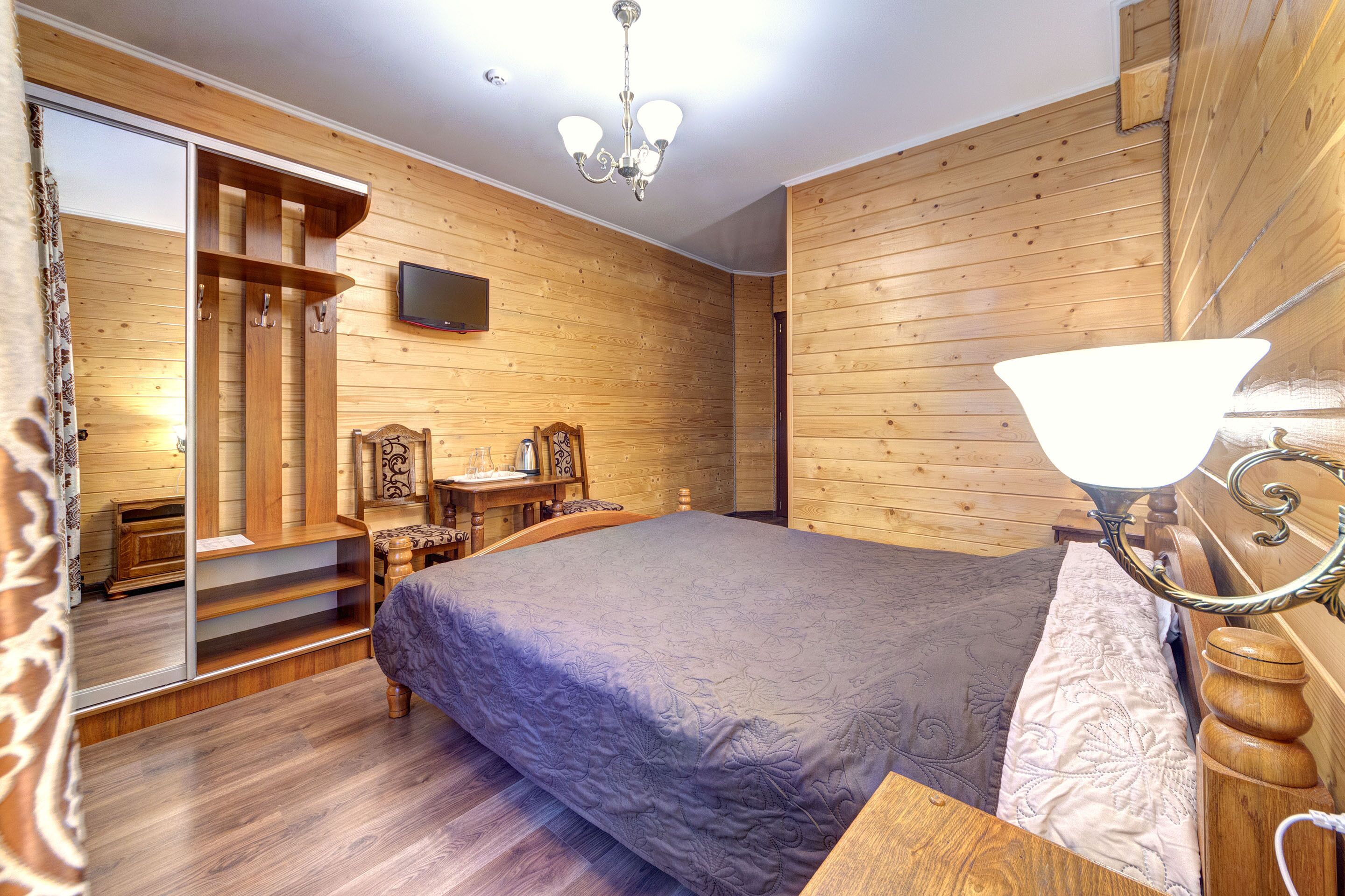 A wooden-paneled bedroom with a bed, a desk, and a chair.
