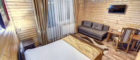 Una habitación de cabaña de madera con una cama, un sofá, un televisor y una mesa de comedor.