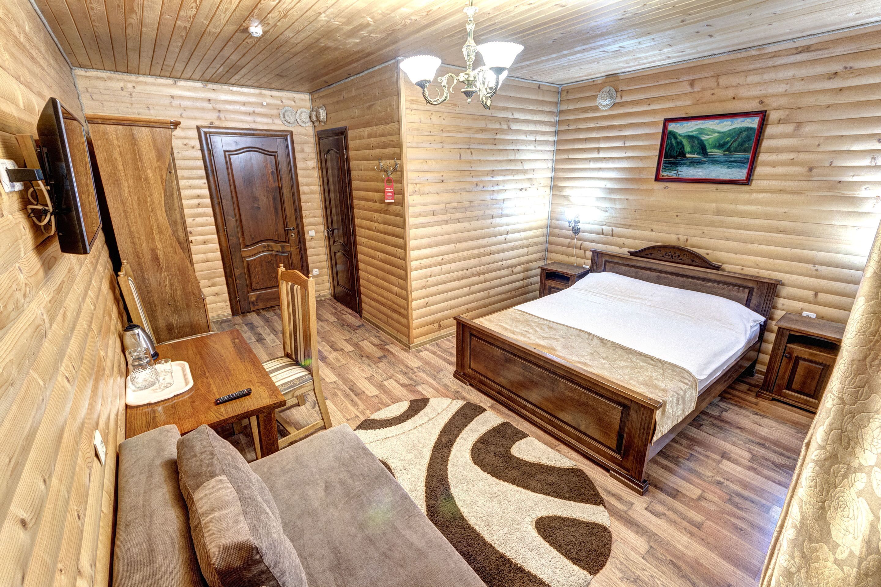 Una habitación con paneles de madera, una cama, una mesita, un sofá y una araña.