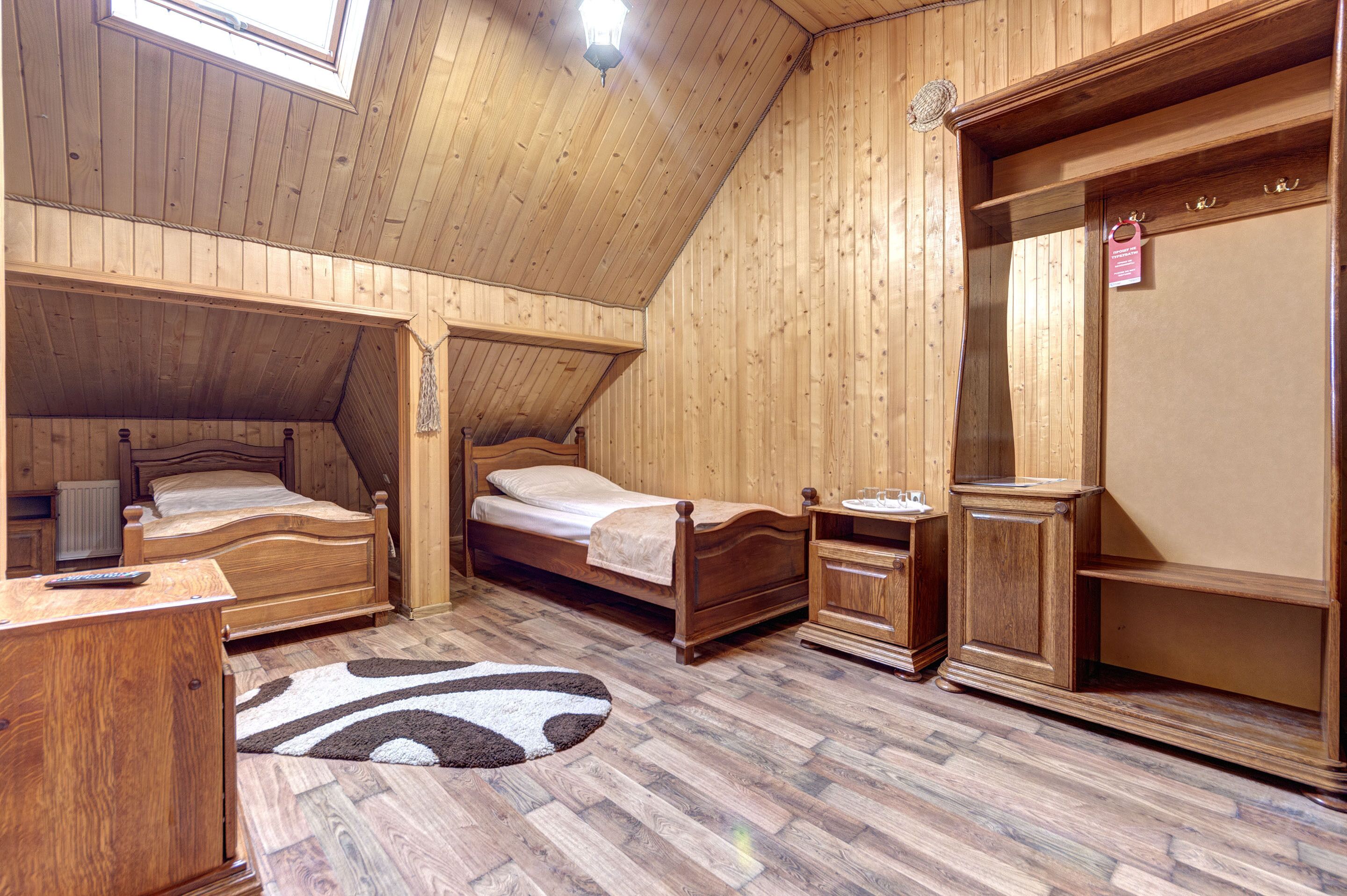 Une pièce en bois avec deux lits, une table de chevet, une commode et une lucarne.