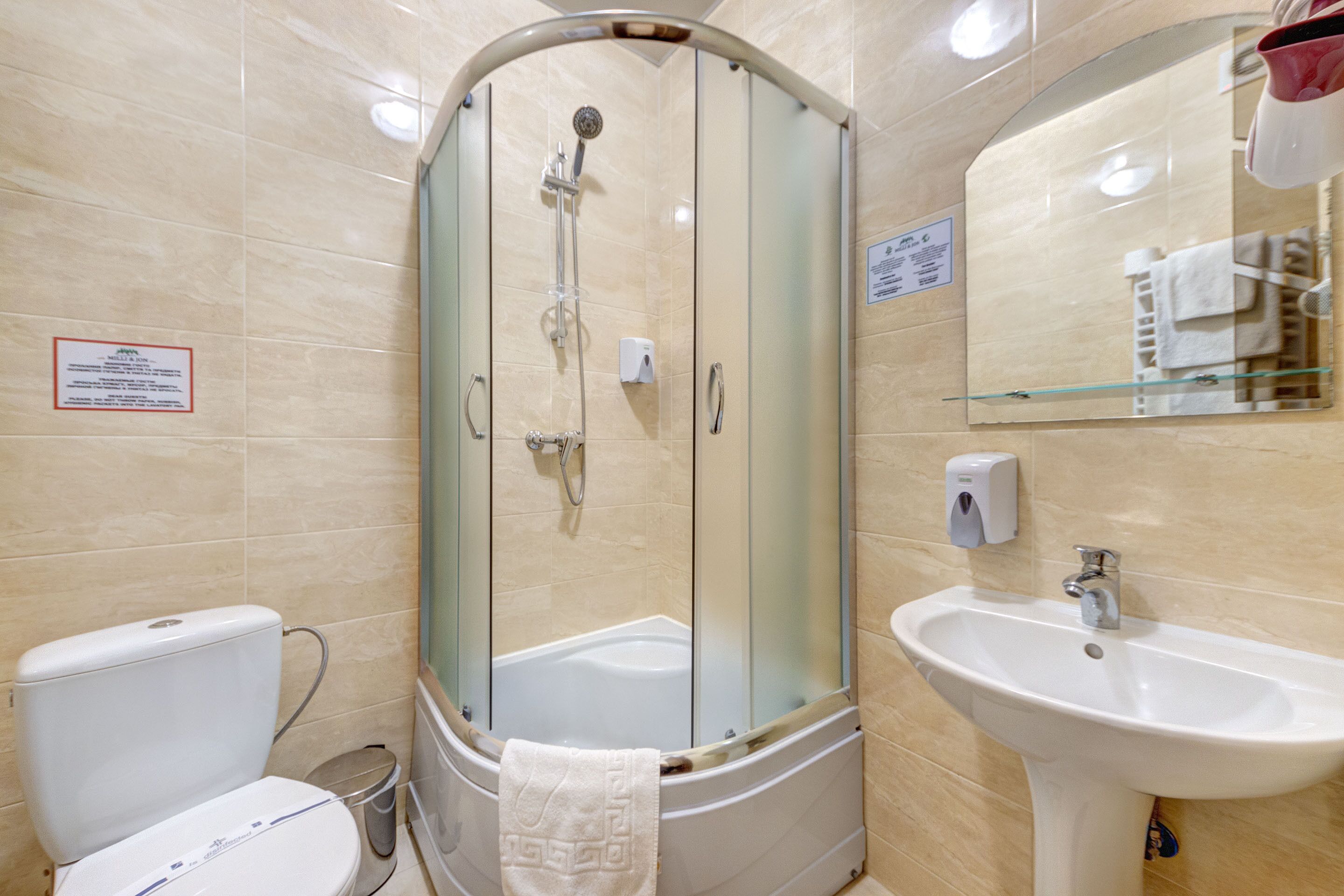 A bathroom with a glass-enclosed shower, a white sink, and a toilet.