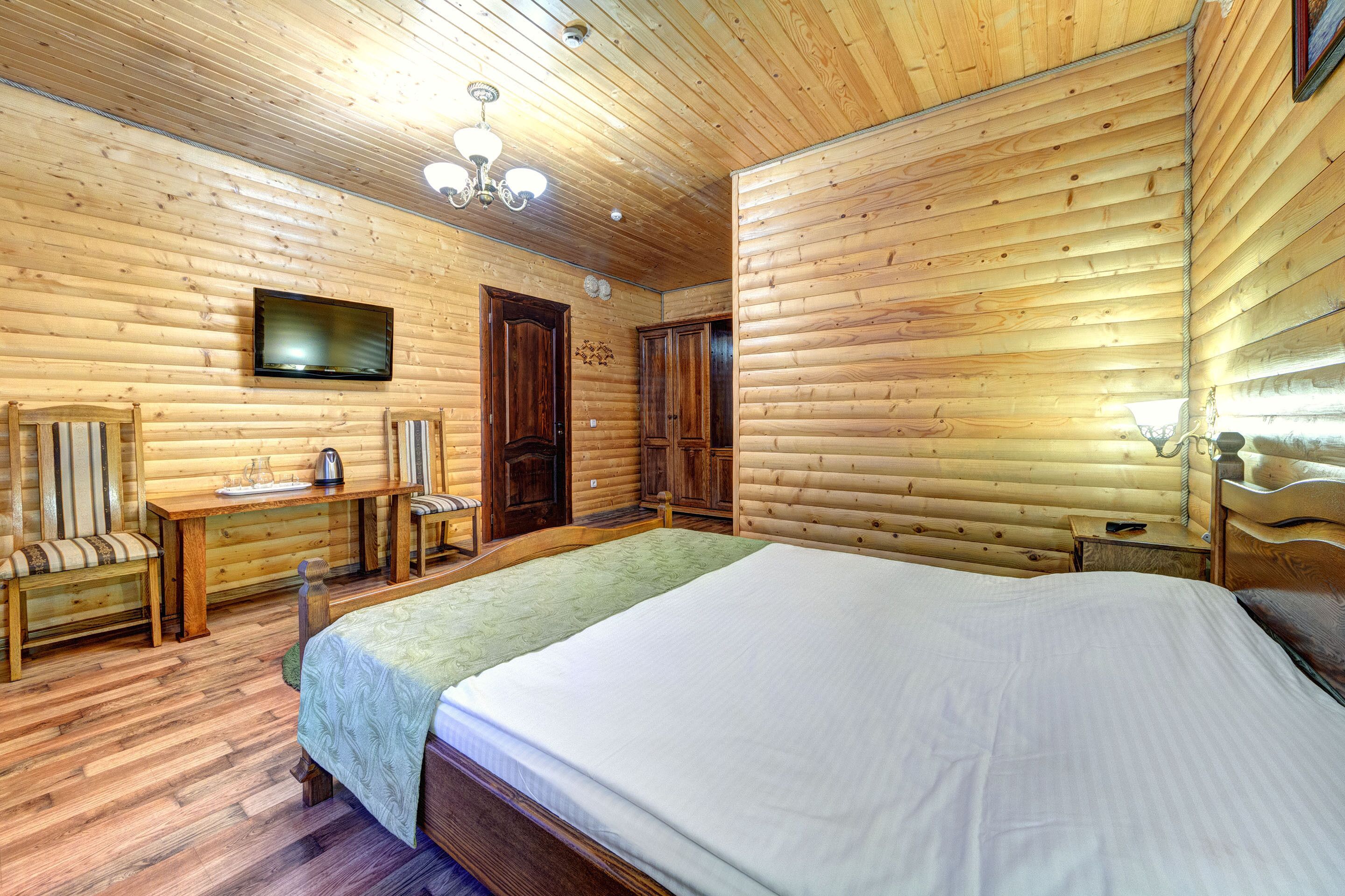 A wooden-paneled room with a bed, a desk, and a television.