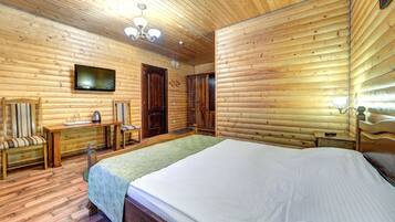 A wooden-paneled room with a bed, a desk, and a television.