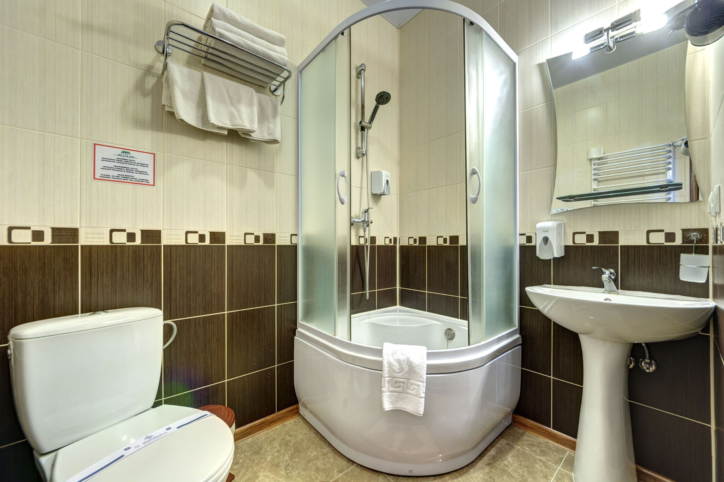A bathroom with a glass-enclosed shower, a toilet, and a sink.
