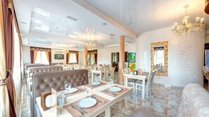 A spacious dining area with multiple tables and chairs, elegant chandeliers, and a marble floor. - Hotel Milli & Jon (Bukovel)