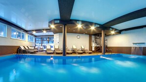 An indoor swimming pool with lounge chairs and a covered seating area. - Hotel Milli & Jon (Bukovel)