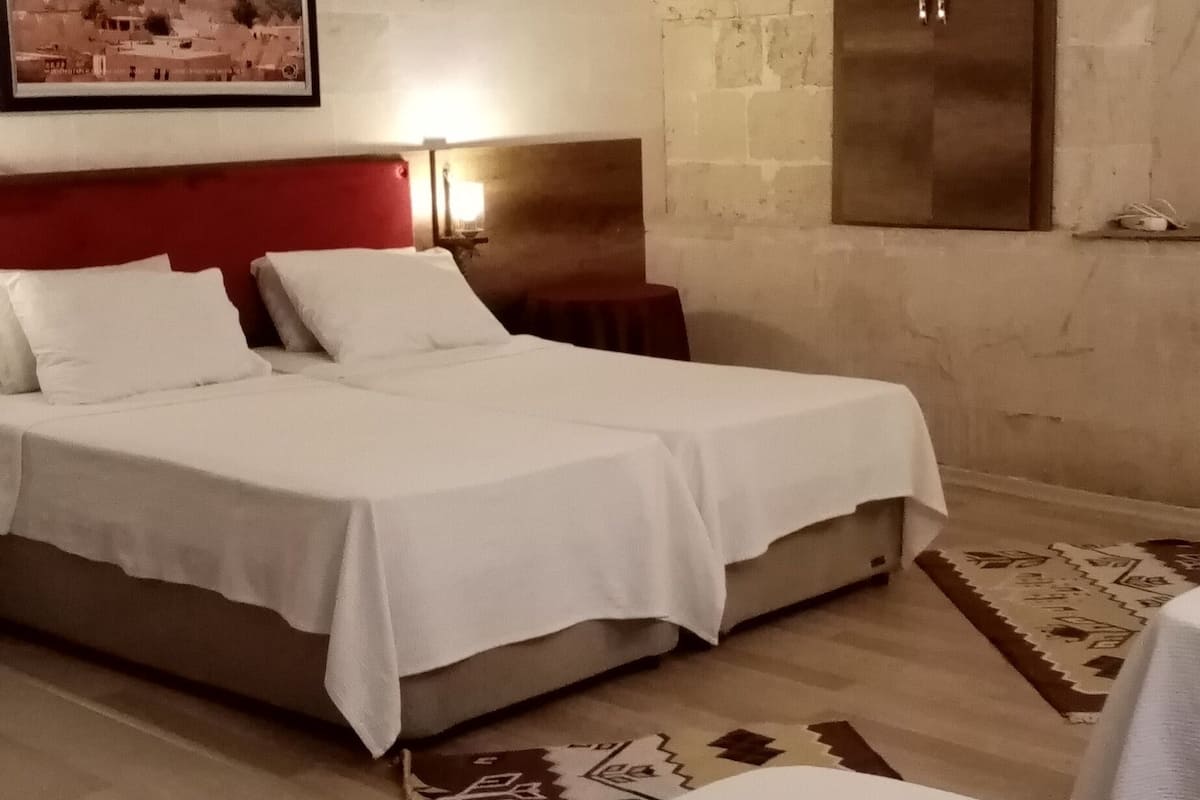 A room with two beds, a wooden wardrobe, and two framed pictures on the wall.