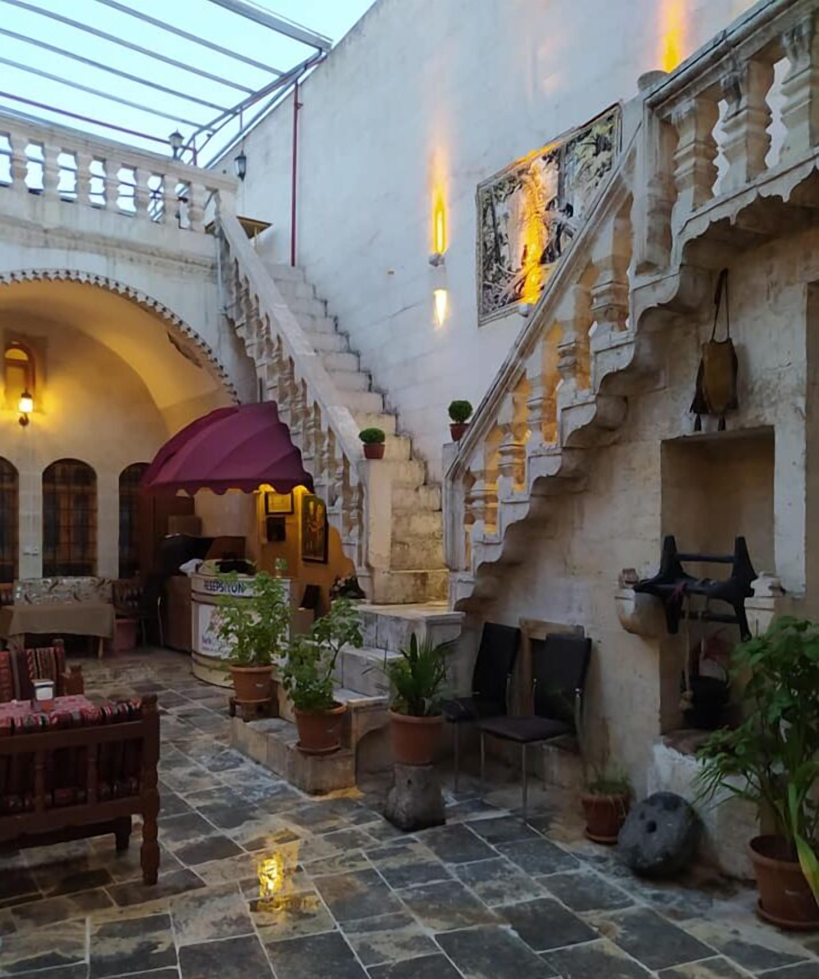 Un cortile con una scala in pietra, piante in vaso e un'area relax con tavolo e sedie.