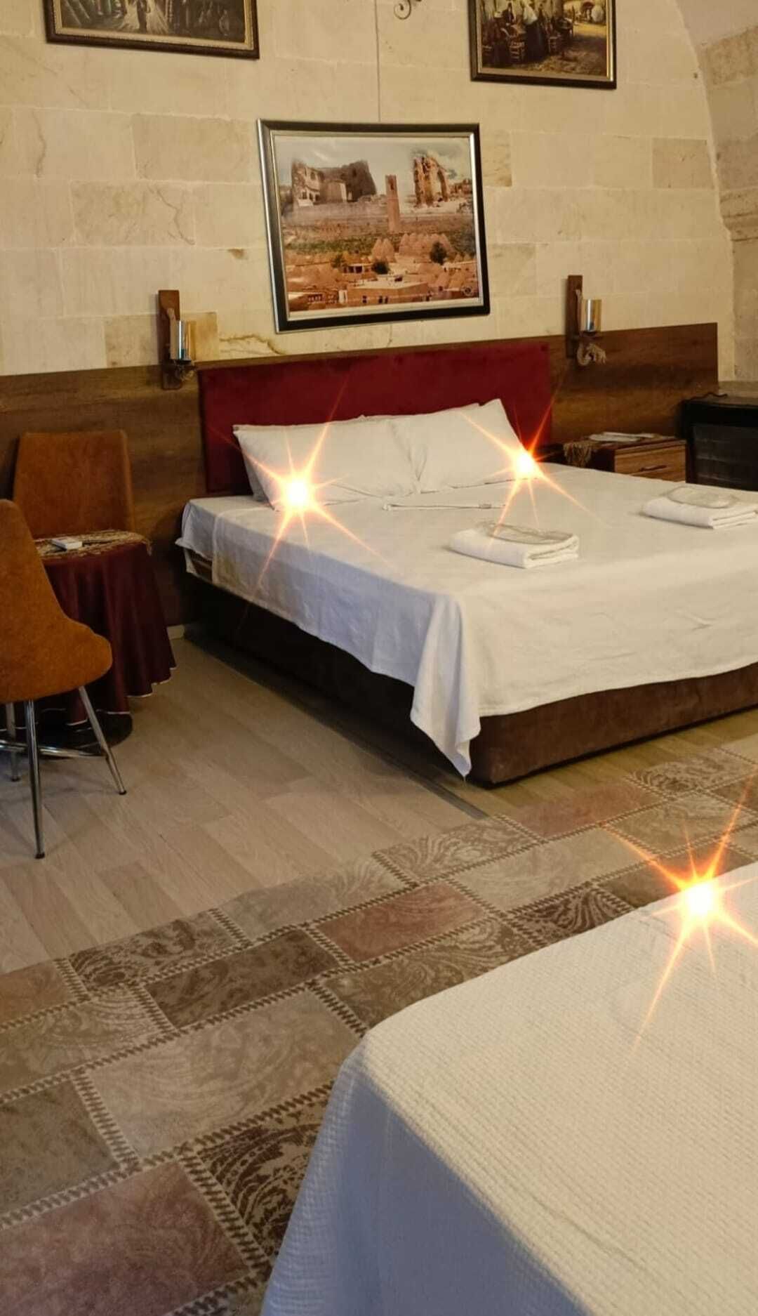 A hotel room with a bed, a chair, a small table, and a wall-mounted shelf.