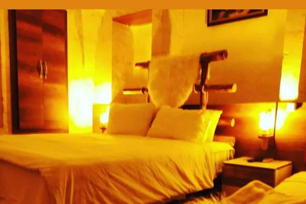 A hotel room with a bed, a nightstand, and a lamp.