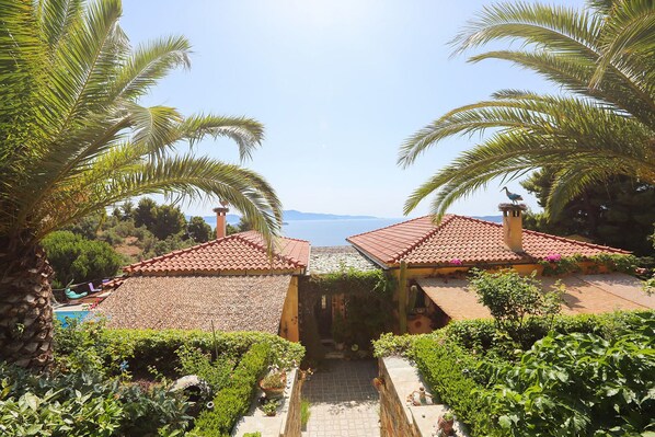Una villa con techo de tejas, piscina y vistas al mar.