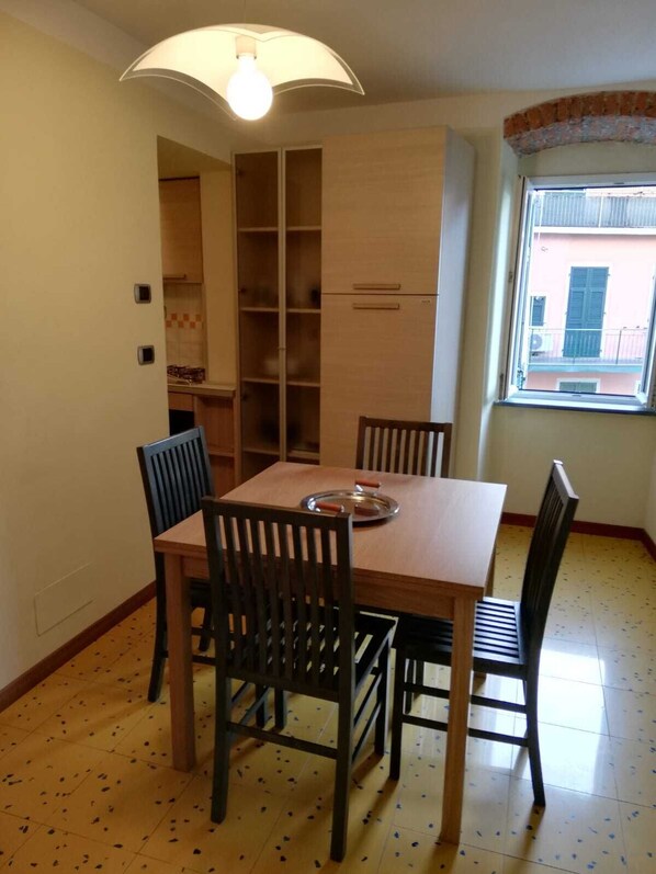 Un coin repas avec une table et des chaises en bois, un meuble encastré et une fenêtre donnant sur des immeubles.