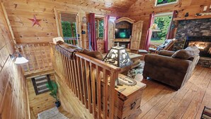 A wooden cabin interior with a staircase, a fireplace, a television, and a cozy seating area. - LAKE BLUE RIDGE VIEW & ACCESS, POOL TBL, PROJECTOR, FIRE PIT, HOT TUB, DOGS OKAY (Blue Ridge)