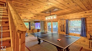 A wooden room with a ping pong table, a television, and a window with curtains. - LAKE BLUE RIDGE VIEW & ACCESS, POOL TBL, PROJECTOR, FIRE PIT, HOT TUB, DOGS OKAY (Blue Ridge)