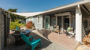 A covered patio with outdoor furniture, a dining table, and a small garden area. - Beachy Getaway–Cozy, Clean & Equipped w/ All Essentials! Relax, Enjoy & Refresh! (St. Augustine)