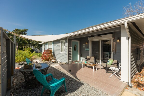 A covered patio with outdoor furniture, a dining table, and a small garden area.