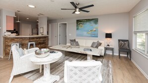 A modern living room with a dining area, a ceiling fan, a painting of water lilies, and a view of the outdoors through a window. - Beachy Getaway–Cozy, Clean & Equipped w/ All Essentials! Relax, Enjoy & Refresh! (St. Augustine)