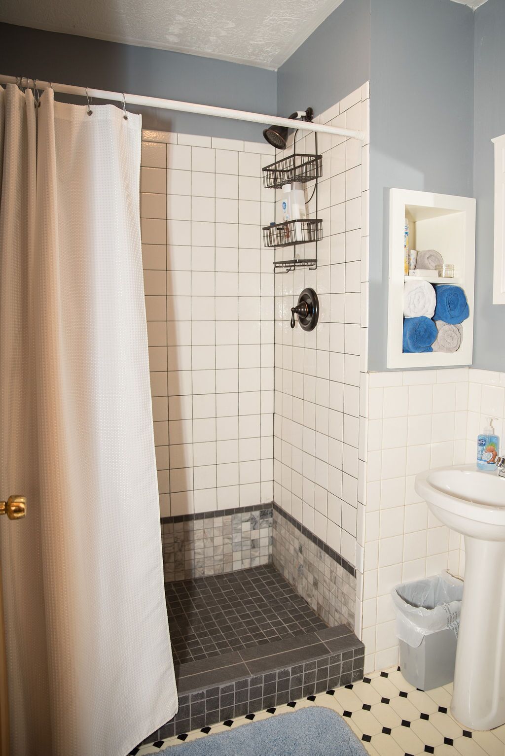 A bathroom with a shower, tiled walls, a sink, and a towel rack.