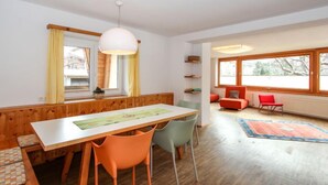 A dining area with a wooden table, orange chairs, and a hanging light fixture. - Apartment Gerda by Interhome (Kaltenbach)