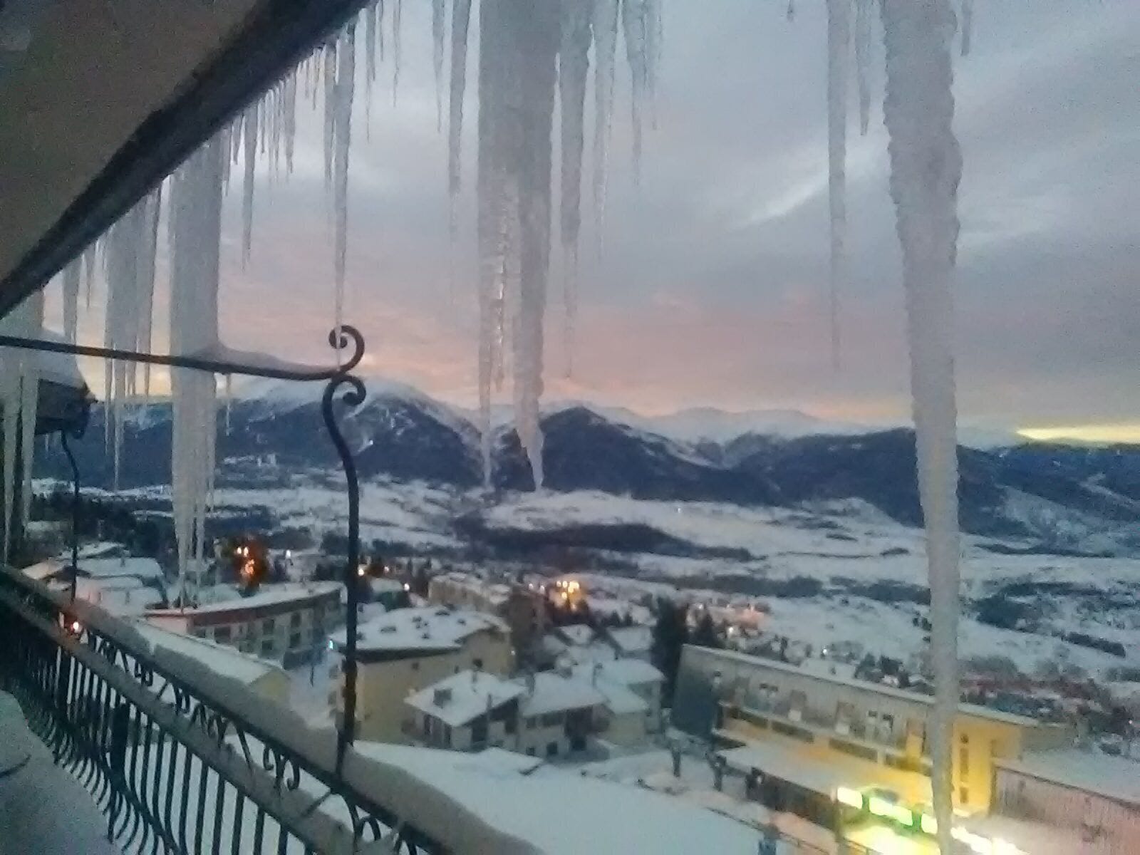 Paisaje montañoso nevado con edificios en primer plano.