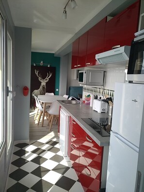 A kitchen with red cabinets, a microwave, a toaster, and a refrigerator. - Beautiful apartment with balcony and panoramic views of the mountains (Font-Romeu-Odeillo-Via)