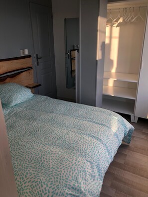 A bedroom with a bed, a wardrobe, and a door. - Beautiful apartment with balcony and panoramic views of the mountains (Font-Romeu-Odeillo-Via)