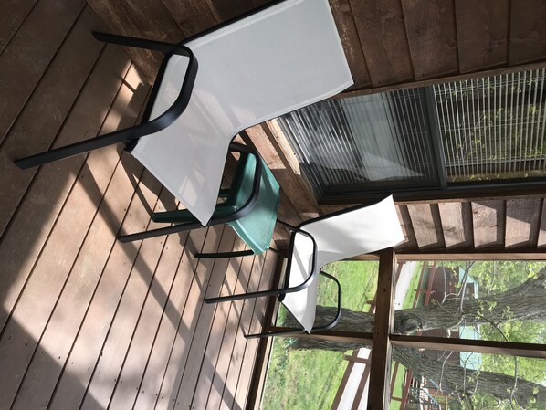 Relax on the deck with two comfortable chairs, surrounded by lush greenery.