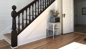 A staircase with dark balusters, a white door, and a small table with a 'Welcome' sign.