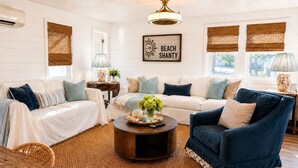 Un salon avec un canapé blanc, un fauteuil bleu et une table basse sur laquelle est posé un vase de fleurs.