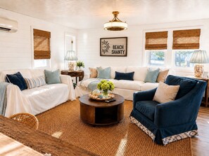 A living room with a white sofa, blue armchair, and a coffee table with a vase of flowers.