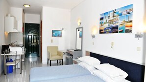 Una habitación de hotel con cama, escritorio, silla, espejo y una pared decorada con imágenes.