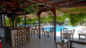 Zona de piscina al aire libre con sillones de descanso y un bar.
