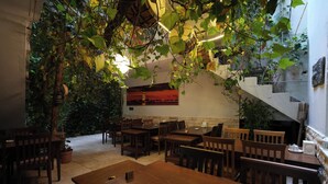A restaurant with wooden tables and chairs, a staircase, and hanging plants. - Ozen Turku Hotel (Denizli)