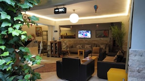 A hotel lobby with a sofa, chairs, a TV, and a WC sign. - Ozen Turku Hotel (Denizli)
