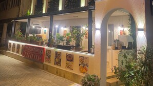 A multi-story building with a restaurant on the ground floor, featuring a signboard and potted plants. - Ozen Turku Hotel (Denizli)