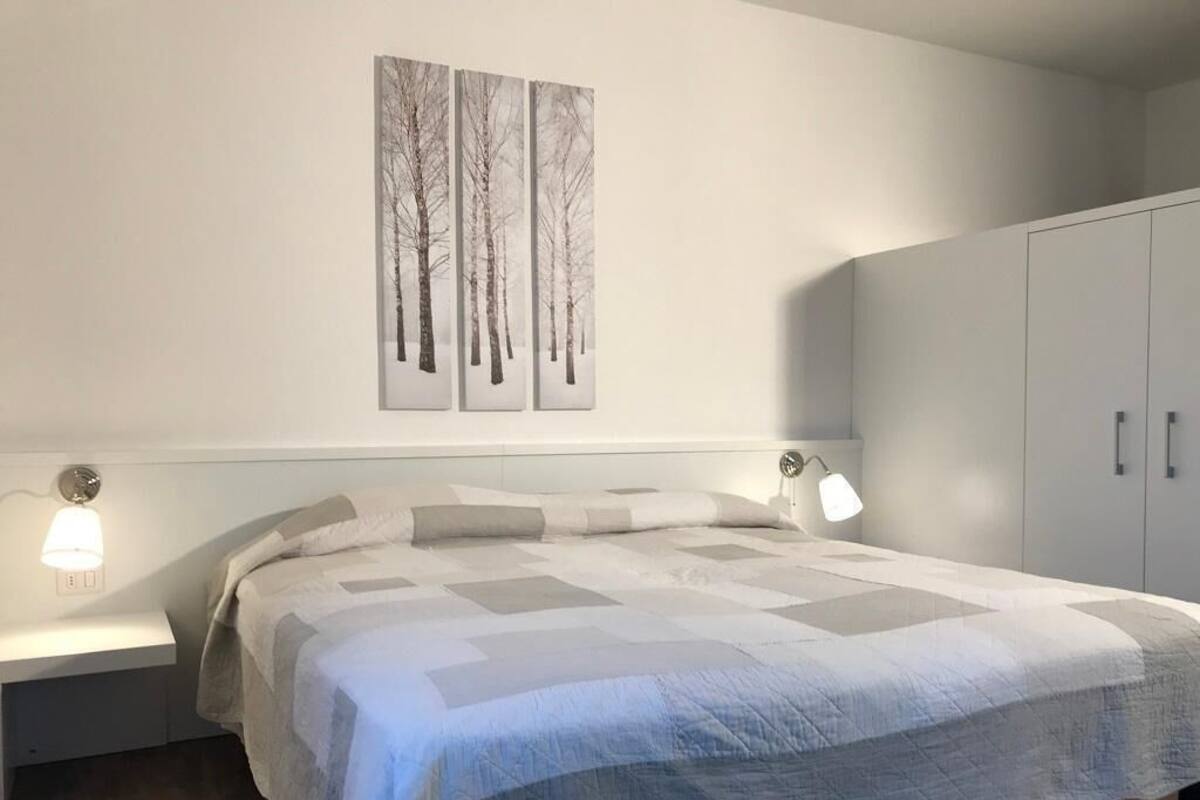 A bedroom with a bed, bedside tables, a nightstand, and a wardrobe.