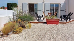 A modern building with a white exterior, large sliding glass doors, and a gravel patio with outdoor furniture.