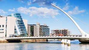A modern bridge with a unique cable design, a waterfront, and contemporary buildings in the background. - Baggot Rath by Interhome (Dublin)