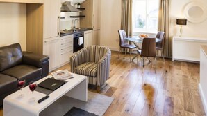 A compact living space with a kitchenette, a dining area, and a seating area with a sofa and armchair. - Baggot Rath by Interhome (Dublin)