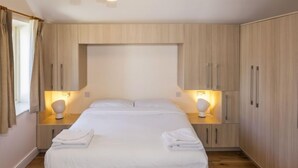 A modern bedroom with a large bed, wooden wardrobe, bedside lamps, and a window with curtains. - Baggot Rath by Interhome (Dublin)