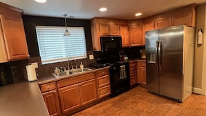 A modern kitchen with wooden cabinets, a stainless steel refrigerator, a microwave, and a coffee maker.
