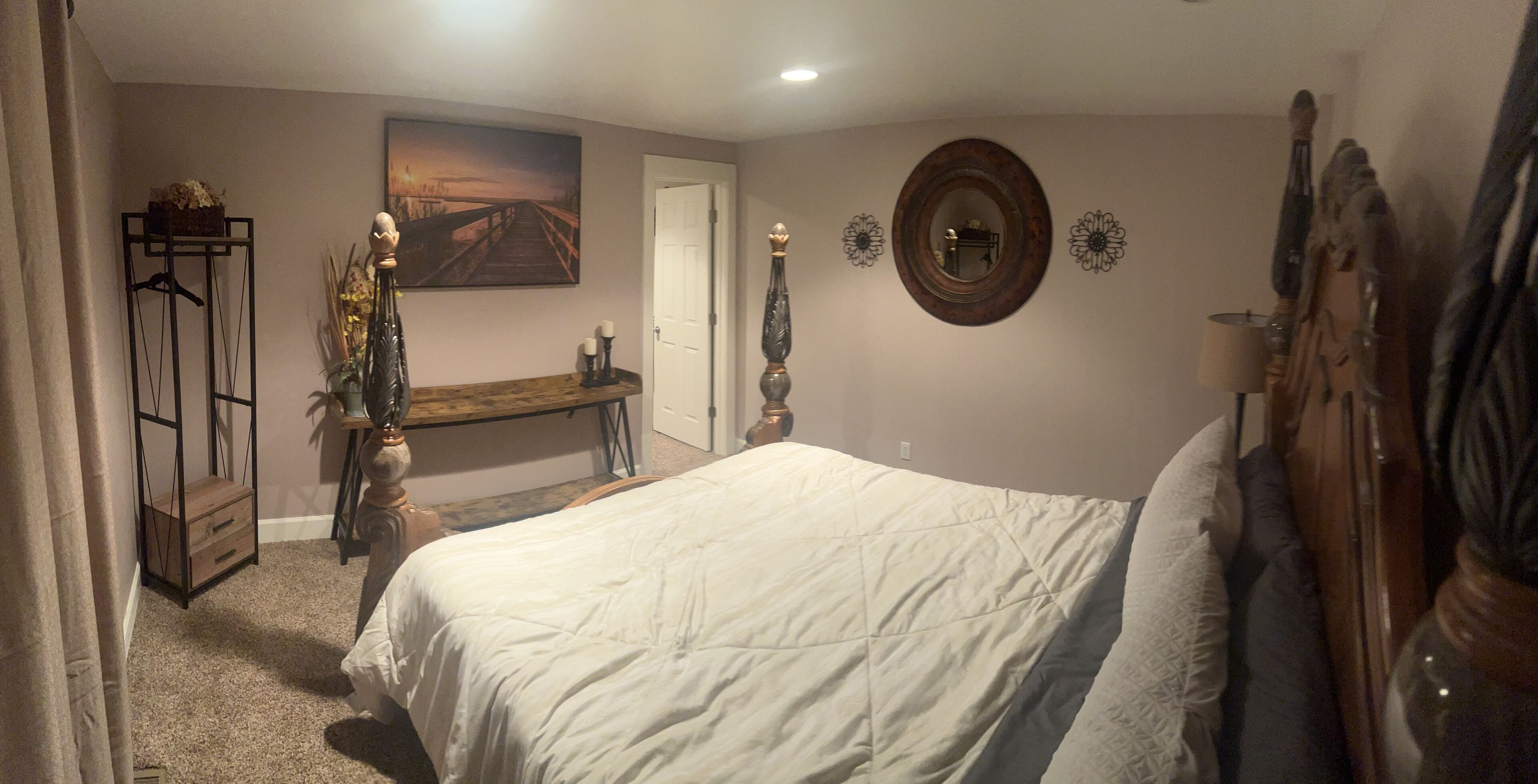 Ein Schlafzimmer mit einem großen Bett, einem Schminktisch, einem Spiegel und einem Bild an der Wand.