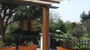 A covered outdoor seating area with lounge chairs and potted plants. - THE TERRACE ON THE PARK (Oristano)