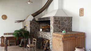 A stone fireplace with a chimney, a wooden bench, a chair, and a potted plant. - THE TERRACE ON THE PARK (Oristano)